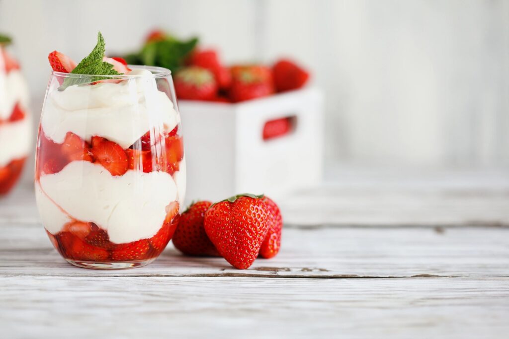 Healthy breakfast of strawberry parfait made with fresh fruit, and yogurt over a rustic white table